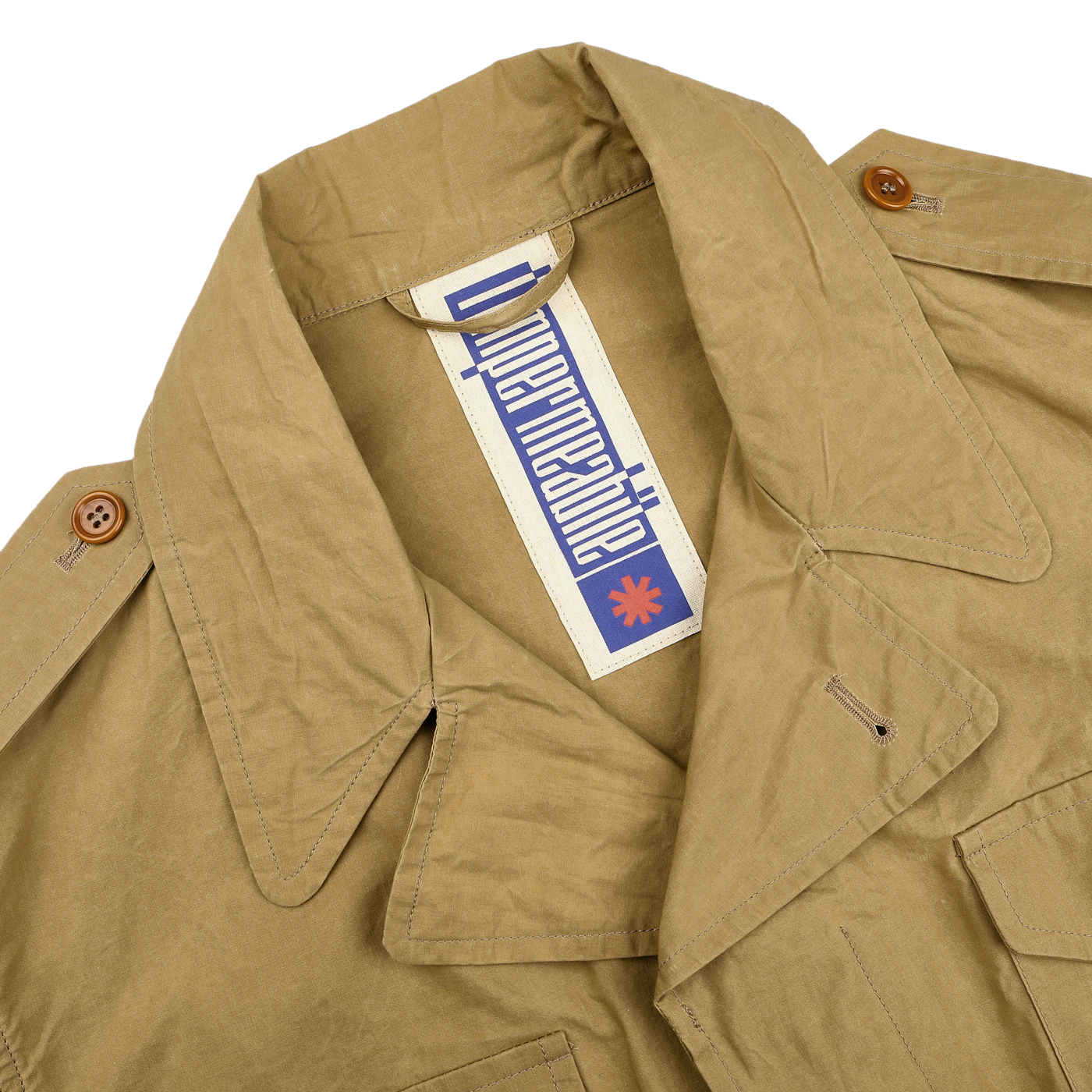 The Khaki Beige Waxed Cotton Smith SFO Jacket by L'Impermeabile displays Italian craftsmanship with a wide collar, brown buttons, and a blue-and-white logo tag featuring a red star. Its water-repellent finish enhances functionality in this uniquely designed piece.