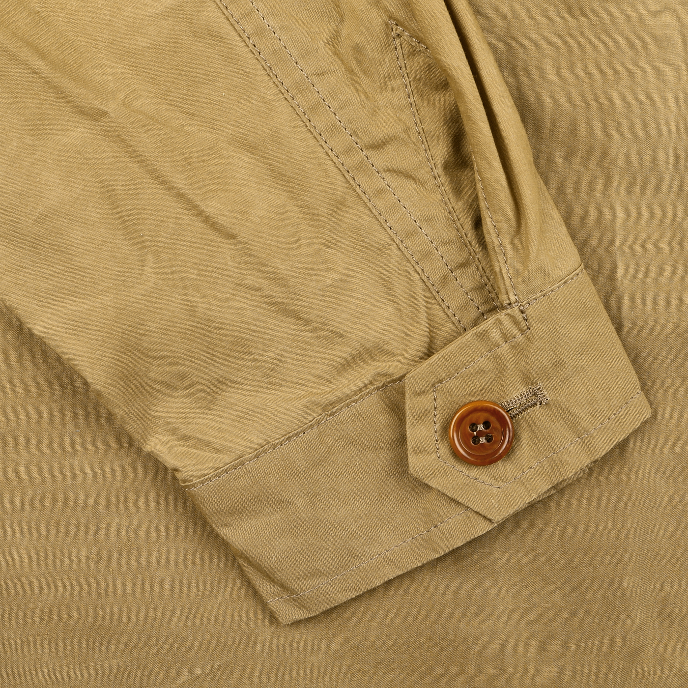 A close-up of the Khaki Beige Waxed Cotton Smith SFO Jacket by L'Impermeabile shows a rolled-up sleeve with a brown buttoned cuff, highlighting the stitching details and Italian craftsmanship.