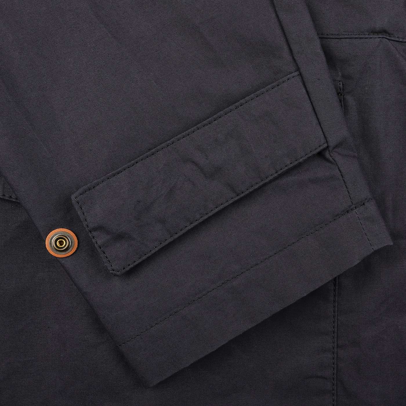 Close-up of the navy blue fabric with a wooden button and rectangular flap pocket, showcasing the craftsmanship of the L'Impermeabile Navy Blue Waxed Cotton Bob Short Parka.