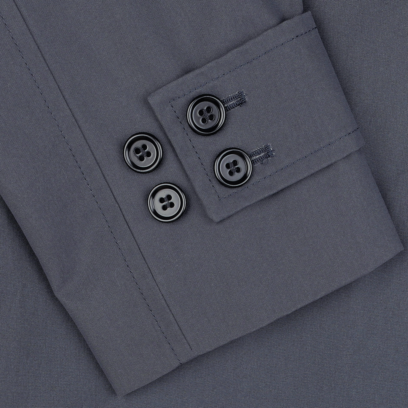 Close-up of a gray dress shirt sleeve featuring a double cuff with four black buttons, two on each side, reminiscent of the refined detailing seen in L'Impermeabile's Washed Blue Waxed Cotton Kamikaze Coat.