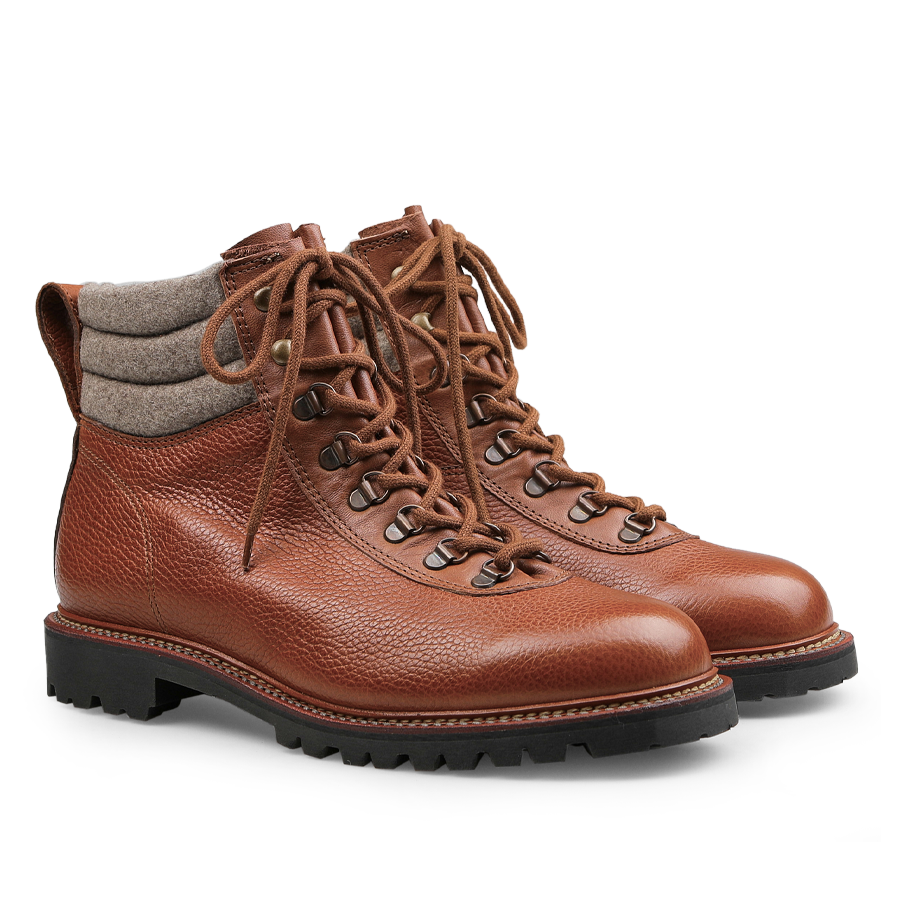 The Mahogany Grain Leather Gebirgsjäger Boots by Ludwig Reiter are crafted from luxurious brown country calf grain leather and feature gray padded collars along with black soles. With laces threaded through durable metal eyelets and a robust Goodyear-welted construction, these boots promise both durability and style for any adventure.