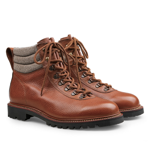 The Mahogany Grain Leather Gebirgsjäger Boots by Ludwig Reiter are crafted from luxurious brown country calf grain leather and feature gray padded collars along with black soles. With laces threaded through durable metal eyelets and a robust Goodyear-welted construction, these boots promise both durability and style for any adventure.