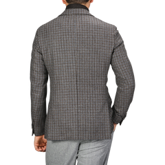 Back view of a person wearing a Luigi Bianchi Brown Houndstooth Wool Cashmere Hybrid Blazer and light grey pants, with their left hand partially visible.