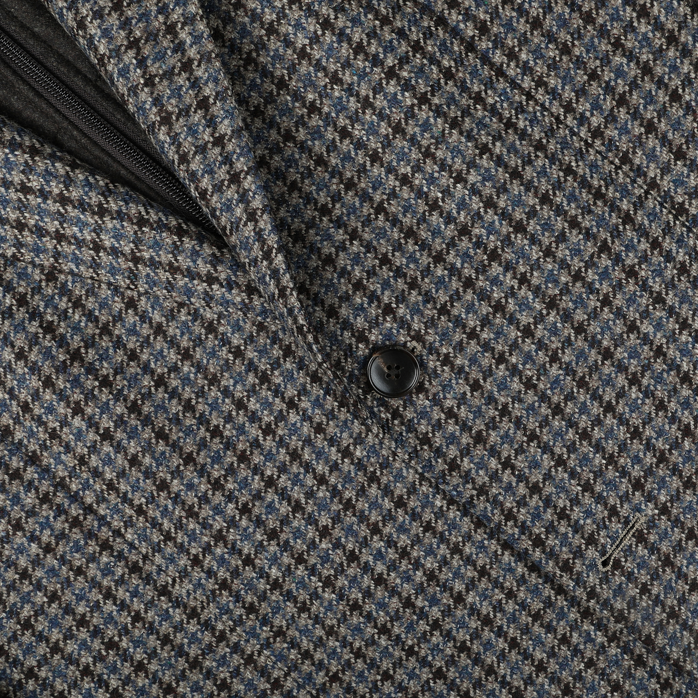 Close-up of a houndstooth patterned fabric coat with a single black button, showcasing the luxurious tailoring of a Luigi Bianchi Brown Houndstooth Wool Cashmere Hybrid Blazer.