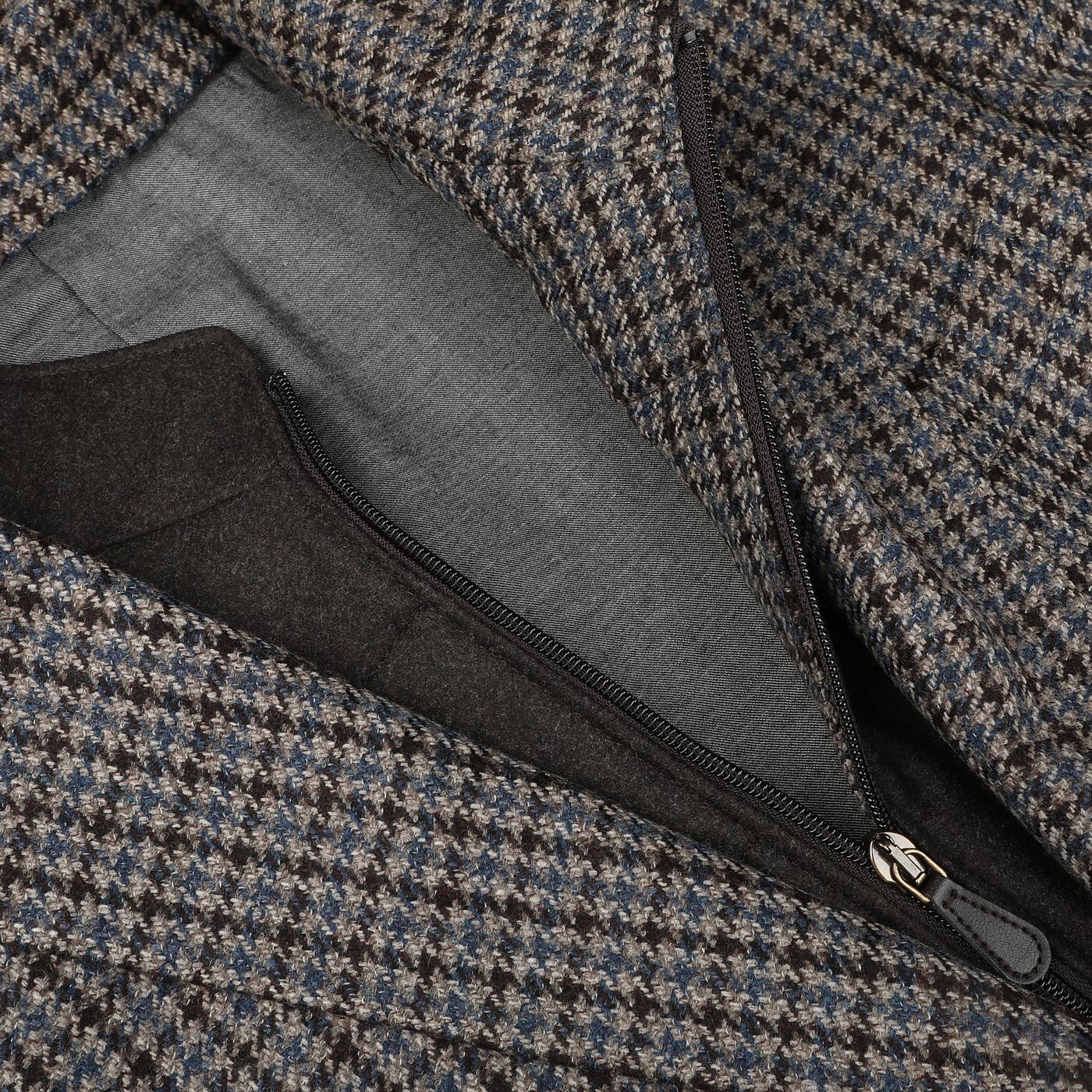 Close-up of the Brown Houndstooth Wool Cashmere Hybrid Blazer from Luigi Bianchi, showcasing its intricate houndstooth pattern and a partially open zipper that reveals a gray lining underneath.