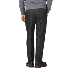 Back view of a person wearing Luigi Bianchi Charcoal Grey Wool Flannel Flat Front Trousers, a gray sweater, and brown dress shoes.