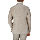 The back view of a man wearing a Light Brown Herringbone Linen Suit by Luigi Bianchi with expertise in tailoring.
