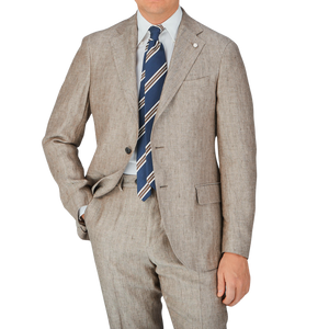 An expert tailor dressed in a Luigi Bianchi Light Brown Herringbone Linen Suit with a blue tie.