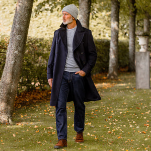 A contemporary fit man in a Navy Blue Wool Cashmere Dream Polo Coat by Luigi Bianchi, walking through a park.