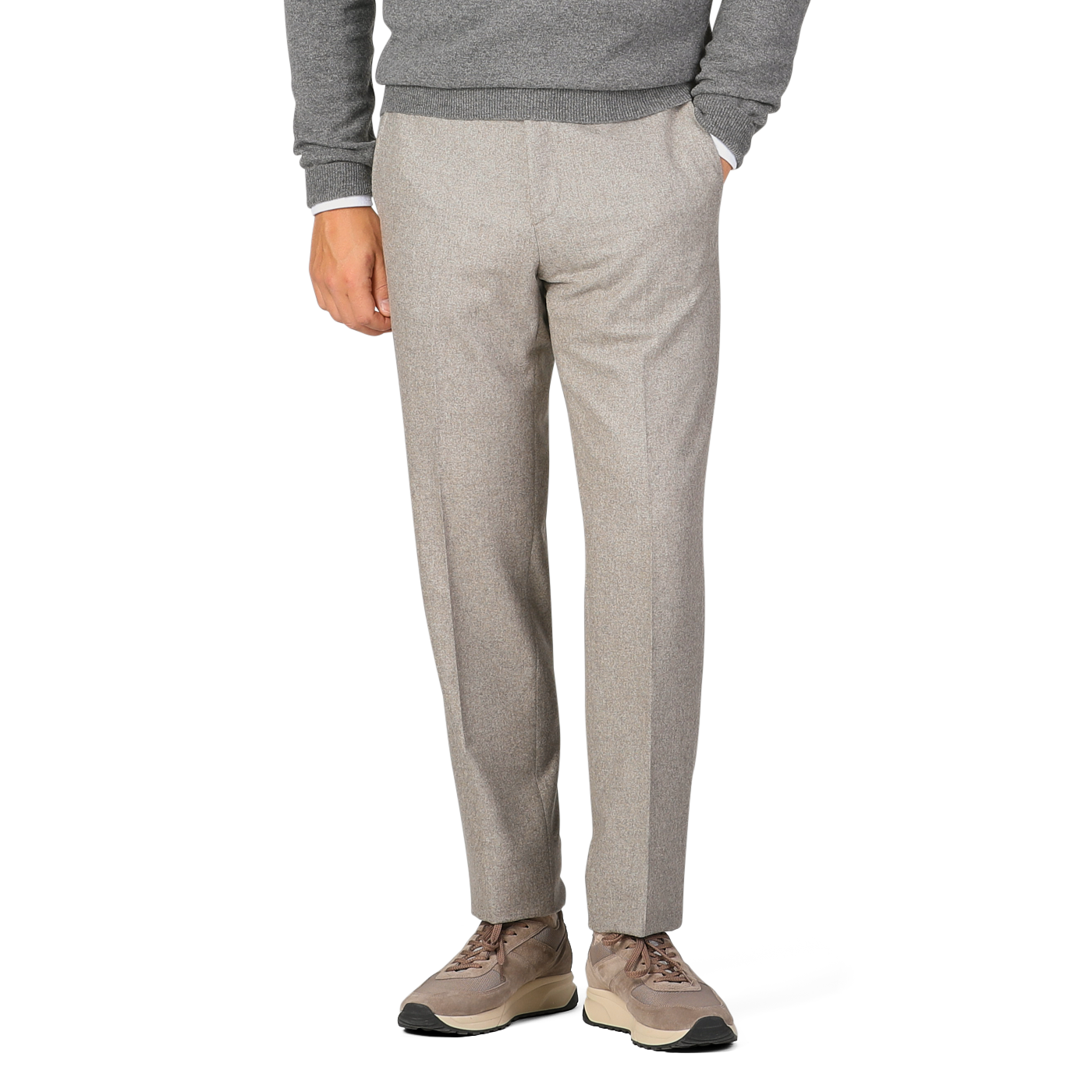 A person dressed in a grey sweater and Luigi Bianchi Oatmeal Beige Wool Flannel Flat Front Trousers is standing with one hand in their pocket. The person is also wearing beige sneakers. Only the lower half of the body is visible.