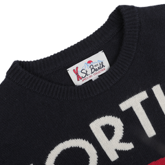 A close-up of a navy blue sweater with elegant white lettering and an MC2 Saint Barth label on the collar, capturing the cozy charm of our Aprés Ski Collection. It's the perfect choice for lounging in style after a day at ski resorts or savoring the winter magic of Cortina, Italy.