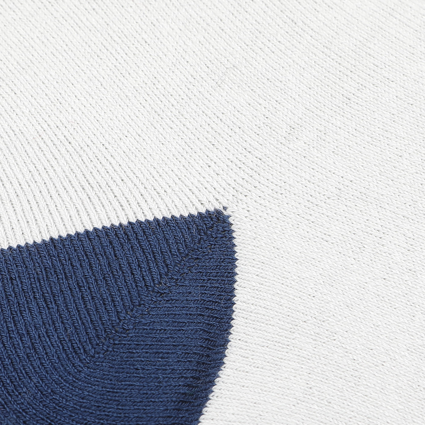 Close-up of a knitted fabric featuring a white background with a triangular navy blue pattern, similar to the design found in MC2 Saint Barth's Blue Cotton Cortina Print Socks.