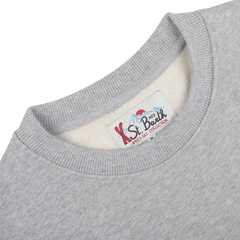 Close-up of a cozy cotton sweater collar with a label reading "MC2 Saint Barth, Grey Melange Cotton Aspen Sweater" in blue and red text, perfect for lounging at Aspen ski resorts.