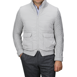 A person wearing an MC2 Saint Barth Light Grey Wool Whistler Padded Jacket over a gray cable-knit sweater and dark gray pants stands against a plain background. The jacket features two front pockets and a zip closure, combining practicality with style.