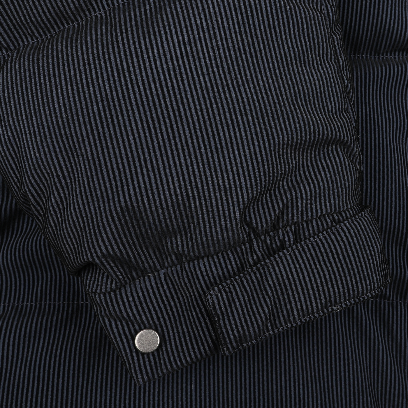 Close-up of the Navy Blue Technical Padded Maier Jacket by MC2 Saint Barth, showcasing a dark pinstriped fabric with an insulated texture and a metal snap button on the cuff. This chic design includes recycled filling for warmth and style reminiscent of Saint Barth.