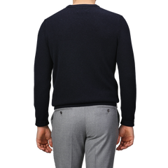 A person is wearing a Navy Blue Wool Cashmere Courchevel Sweater from MC2 Saint Barth and gray pants, facing away from the camera with their arms relaxed by their sides.