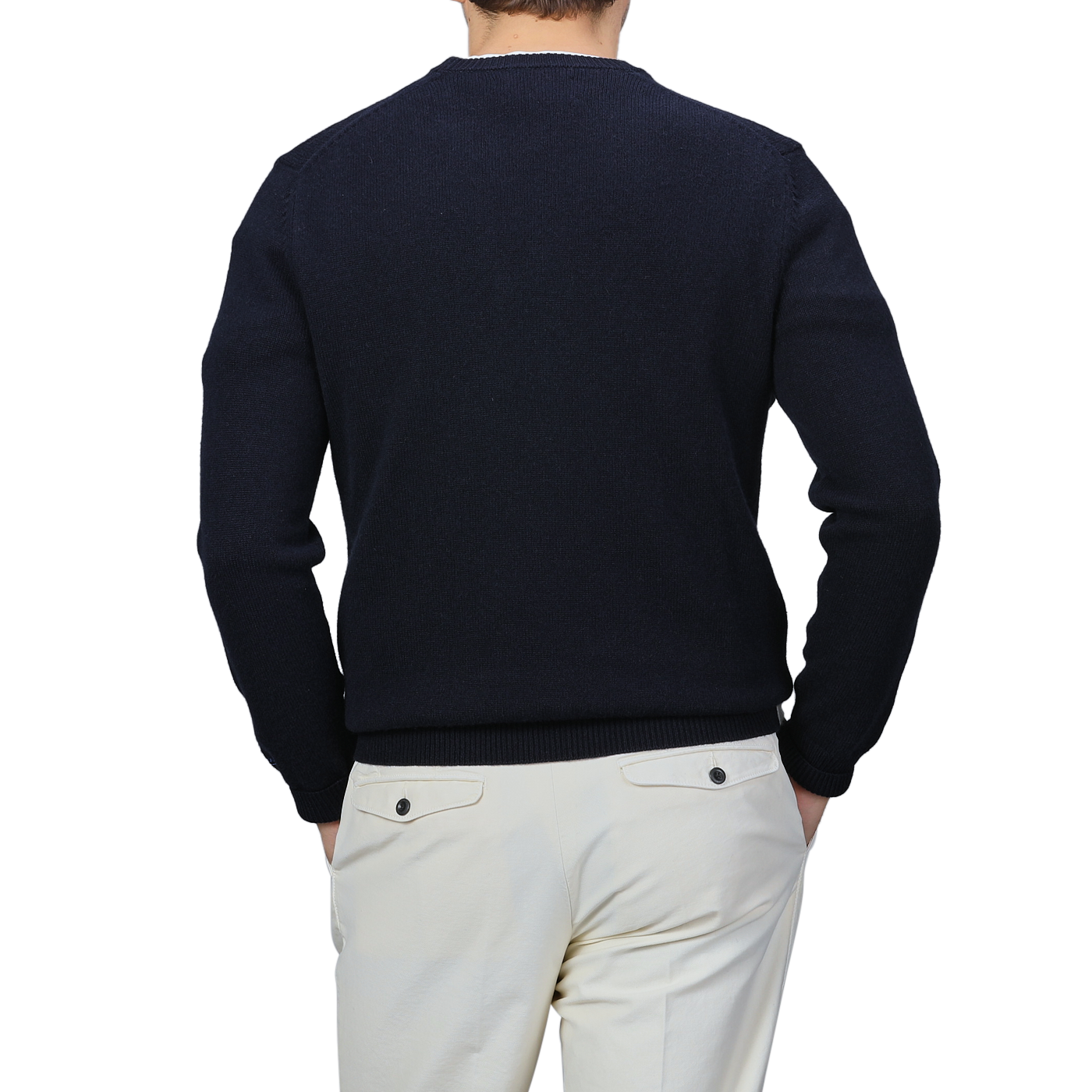 A person wearing the Navy Wool Cashmere Cortina Sweater from MC2 Saint Barth and light-colored pants stands with their back to the camera, channeling the sleek elegance of the Aprés Ski Collection, as if ready to step onto the snowy trails of Cortina, Italy.