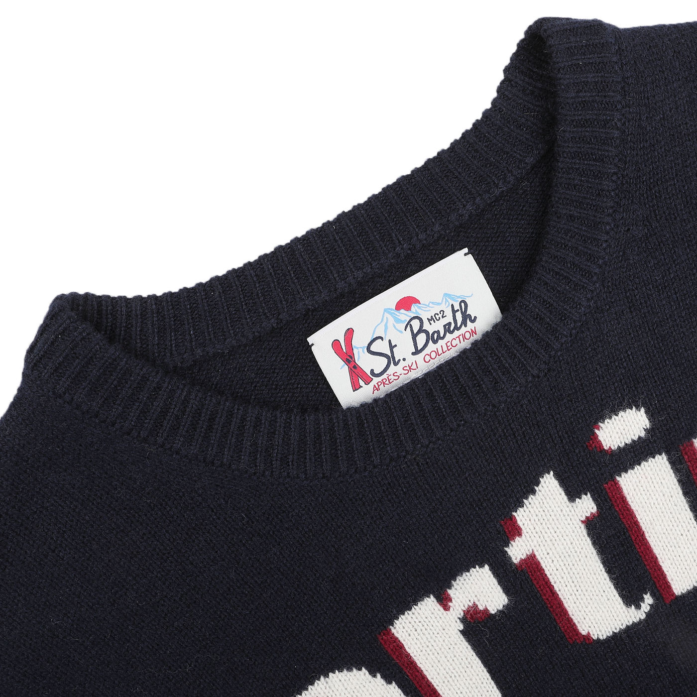 An image highlighting a navy blue sweater with an embroidered design and a label from the "MC2 Saint Barth" brand, part of their "Navy Wool Cashmere Cortina Sweater," ideal for relaxing evenings after skiing at resorts such as Cortina in Italy.