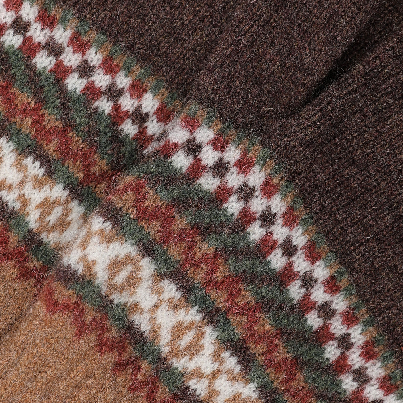 Close-up of a classic pattern on finely knitted fabric, reminiscent of Mackie designs, featuring alternating stripes in brown, white, green, and orange hues on the Brown Lambswool Knitted Gloves.