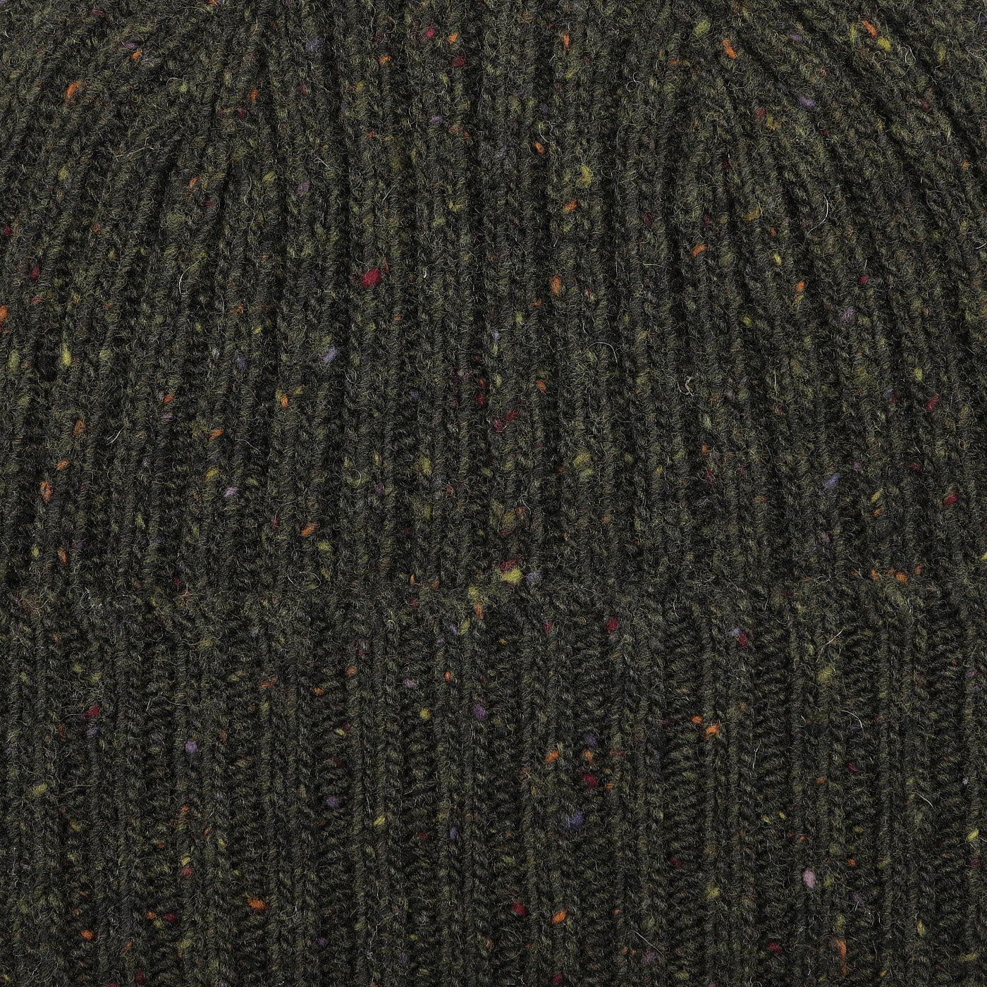 A close-up of the Dark Green Melange Wool Donegal Beanie by Mackie reveals a dark green mélange knit fabric with multicolored specks and a ribbed texture, evoking traditional Donegal wool craftsmanship.