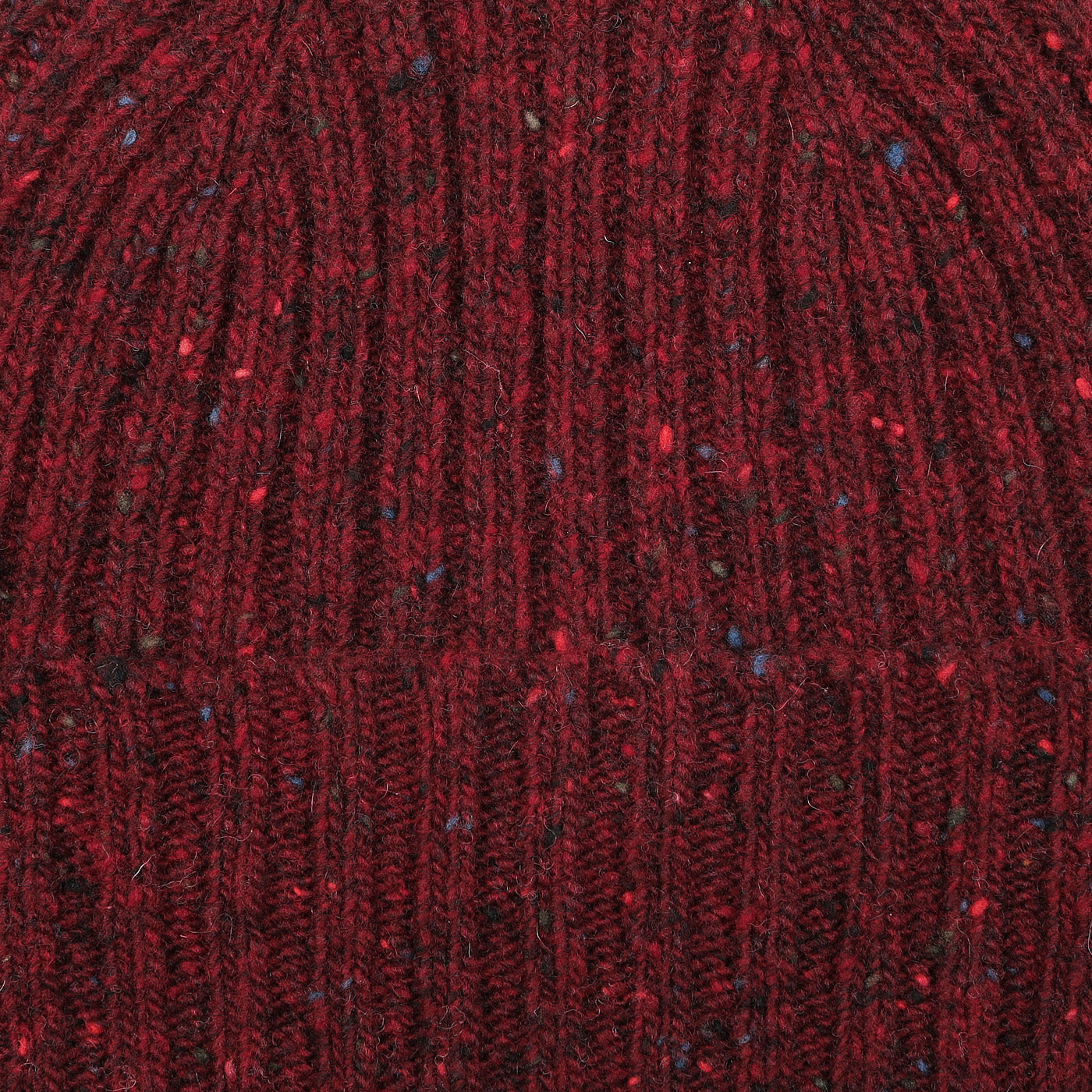 Close-up of the Red Melange Wool Donegal Beanie by Mackie, highlighting the multicolored flecks and intricate stitch detail typical of Scottish knitwear.