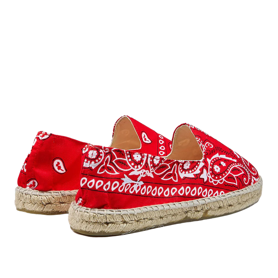 A pair of Red Cotton Bandana Print Manebi espadrille shoes on a striped background.