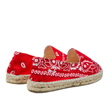 A pair of Red Cotton Bandana Print Manebi espadrille shoes on a striped background.