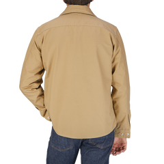 The back view of a man wearing a Camel Beige Cotton Ripstop Country Overshirt by Manifattura Ceccarelli.