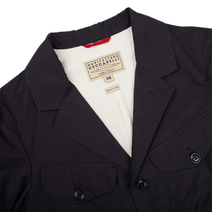 A navy blue ripstop cotton bush jacket by Manifattura Ceccarelli with a red label on it.