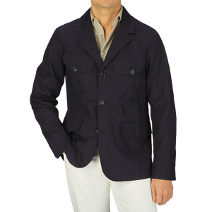A man wearing a navy blue Ripstop cotton Bush Jacket from Manifattura Ceccarelli and white pants.
