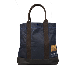 A Navy Blue waxed cotton tote bag with brown handles by Manifattura Ceccarelli.