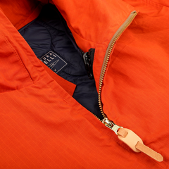 Close-up of the Orange Cotton Nylon Ripstop All Seasons Blazer Coat by Manifattura Ceccarelli, showcasing a partially unzipped zipper with a tan leather pull tab and an interior label. This Ripstop fabric adds style and durability to your look.