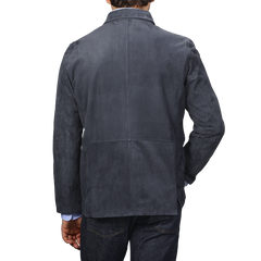 Back view of a person wearing the Denim Blue Suede Unlined Jacket by Manto and blue jeans against a plain background.