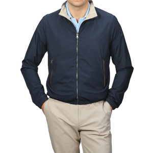 A person is wearing the Manto Navy Beige Reversible Nylon Blouson, featuring a beige collar, and matching beige pants. The slim-fit, water-resistant jacket is zipped up with hands in the pockets.