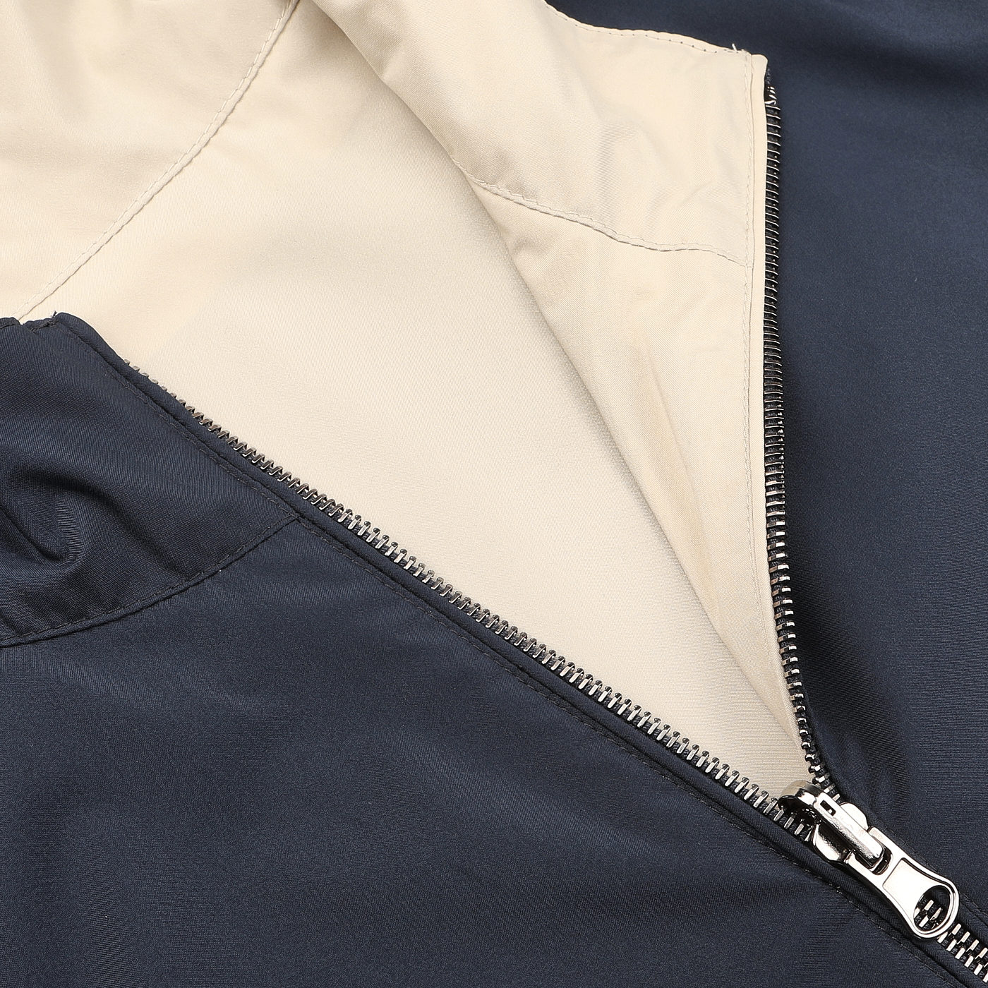 Manto's Navy Beige Reversible Nylon Blouson features a close-up of the partially unzipped design, revealing its beige lining. Made from water-resistant nylon, this slim fit jacket effortlessly combines style and functionality.