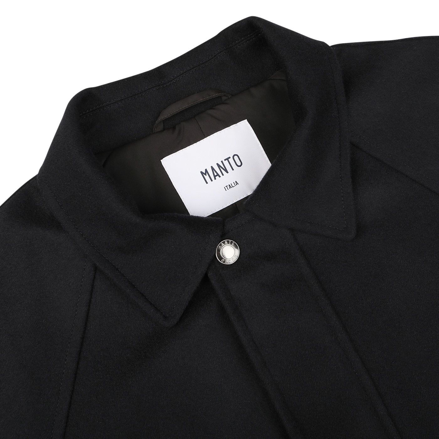 Close-up of the **Navy Blue Cashmere Car Coat** by **Manto**, featuring a pointed collar and a single front button. The label inside reads "Manto Italy." The luxurious cashmere outer exudes sophistication.