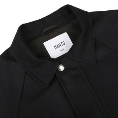 Close-up of the **Navy Blue Cashmere Car Coat** by **Manto**, featuring a pointed collar and a single front button. The label inside reads "Manto Italy." The luxurious cashmere outer exudes sophistication.