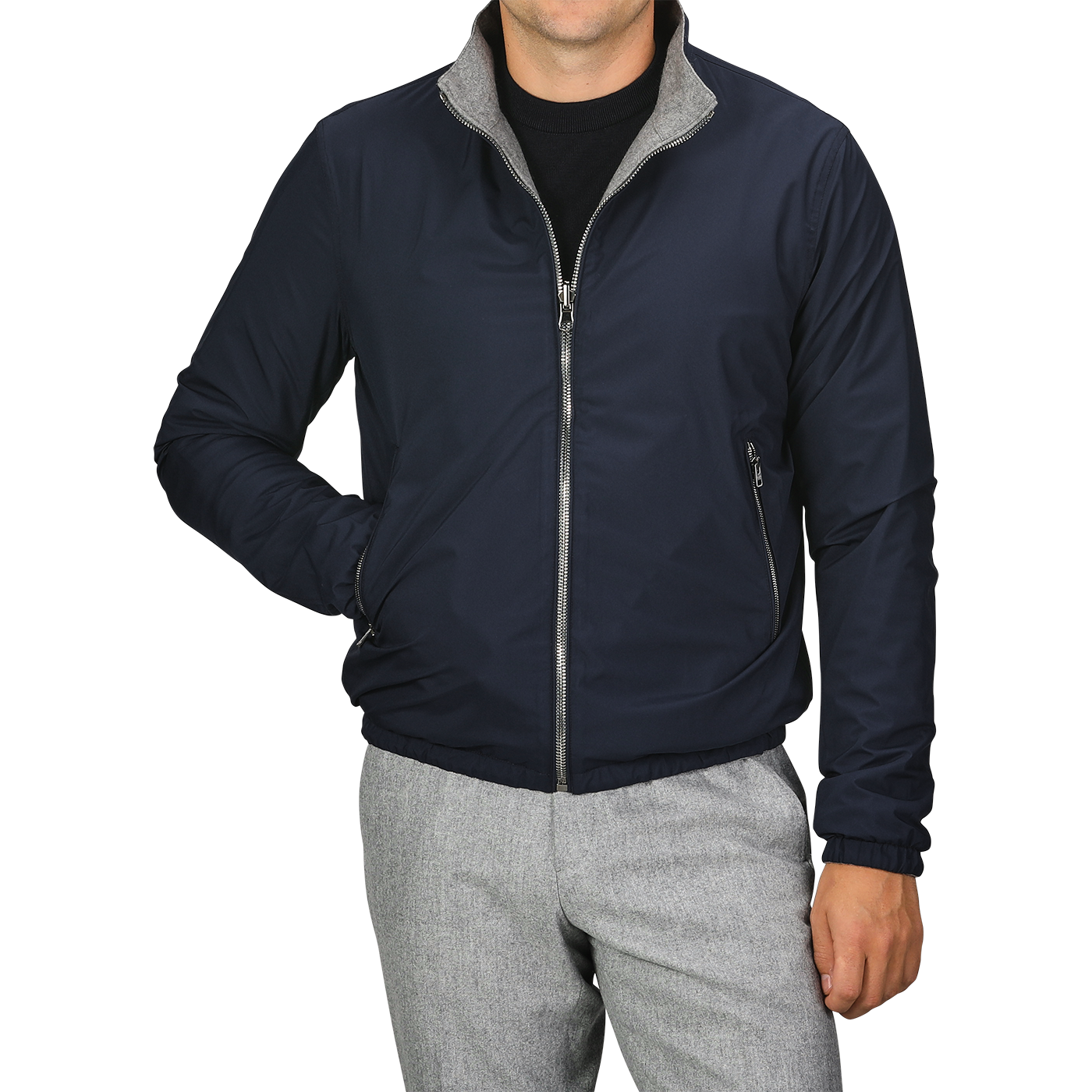 A person dressed in the Manto Navy Grey Cashmere Nylon Reversible Blouson with grey trim and light grey pants. The blouson is zipped up, and the person has their left hand in their pocket, with their face out of view.