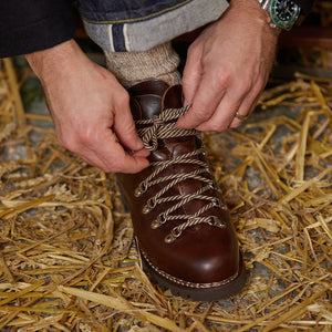 A man is lacing up a Marron Lis Ecorce Leather Avoriaz hiking boot by Paraboot.