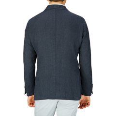 Rear view of a person wearing a Massimo Alba Black Washed Linen Unstructured Blazer in dark blue and white pants.