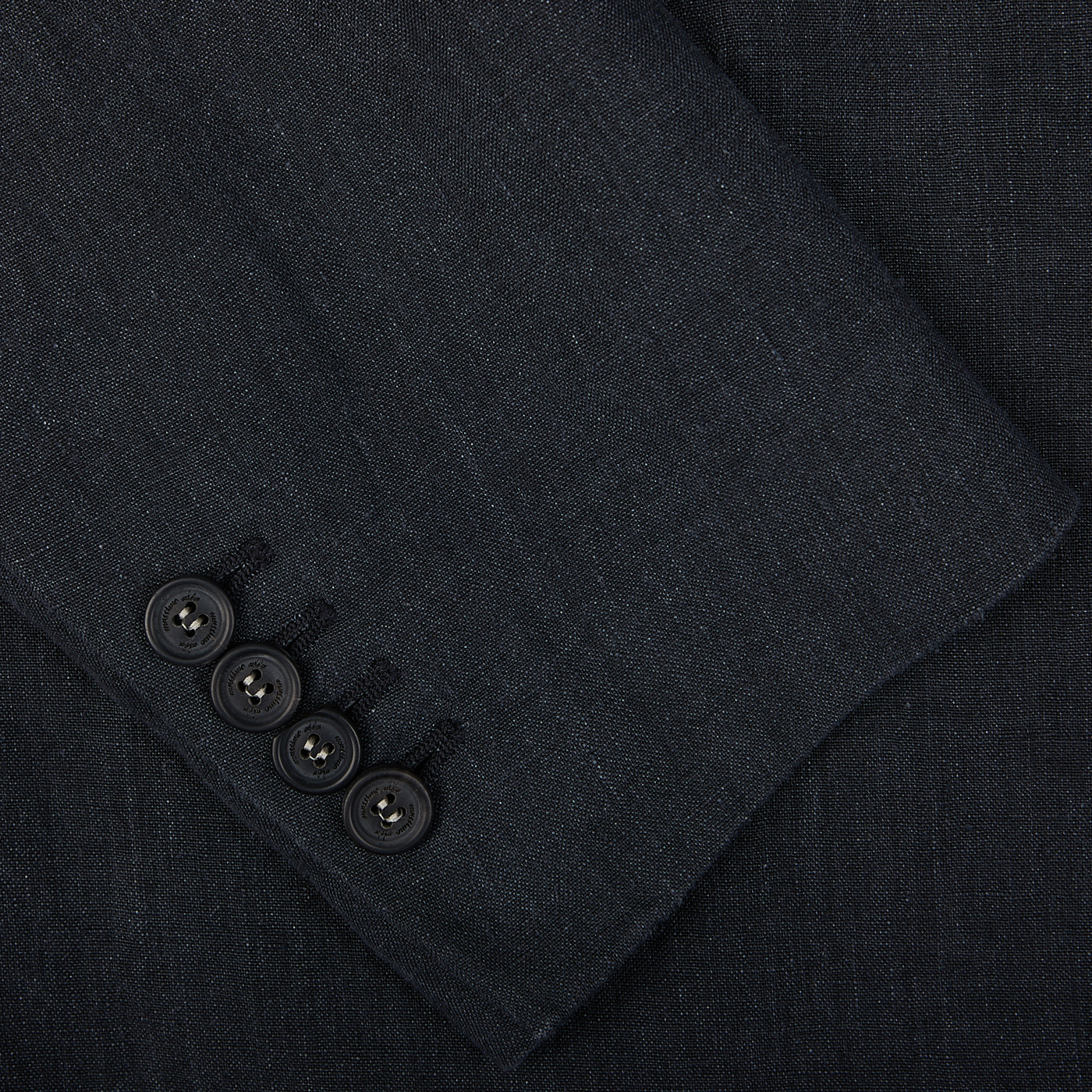Four black buttons on a dark fabric of an Massimo Alba Black Washed Linen Unstructured Blazer, possibly a sleeve detail of the garment.
