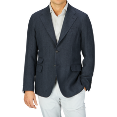 A man wearing a Massimo Alba Black Washed Linen Unstructured Blazer and white pants against a grey background.