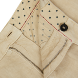 Close-up of a light beige linen garment with a dotted lining, featuring a zipper and button closure with red stitching detail on Massimo Alba casual trousers.
