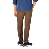 Man standing sideways wearing Massimo Alba Light Brown Linen Casual Trousers made in Italy, a blue shirt, and blue sneakers.