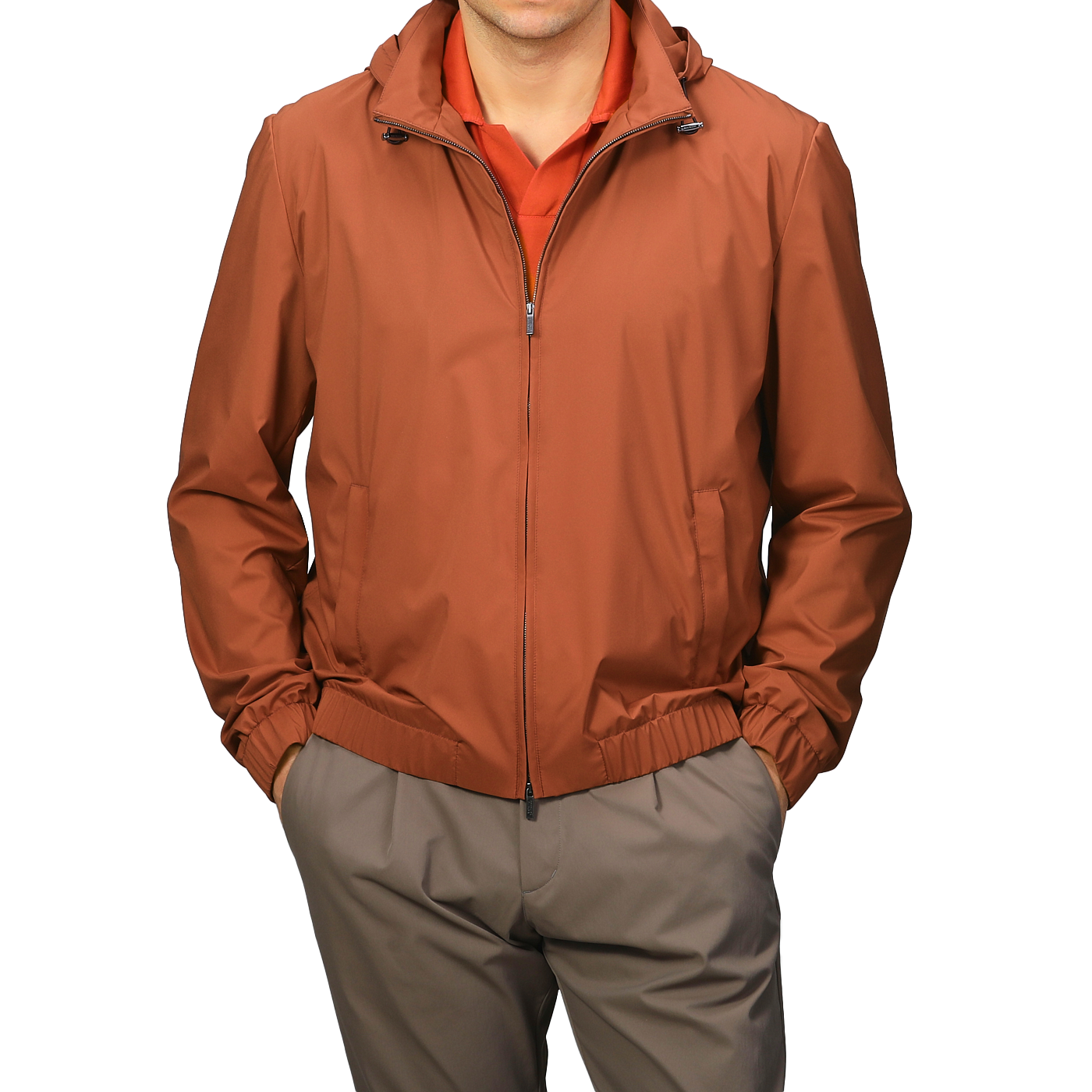 A man wearing a Terracotta Brown Nylon Hooded Blouson Jacket by Maurizio Baldassari over a red shirt, paired with khaki pants.