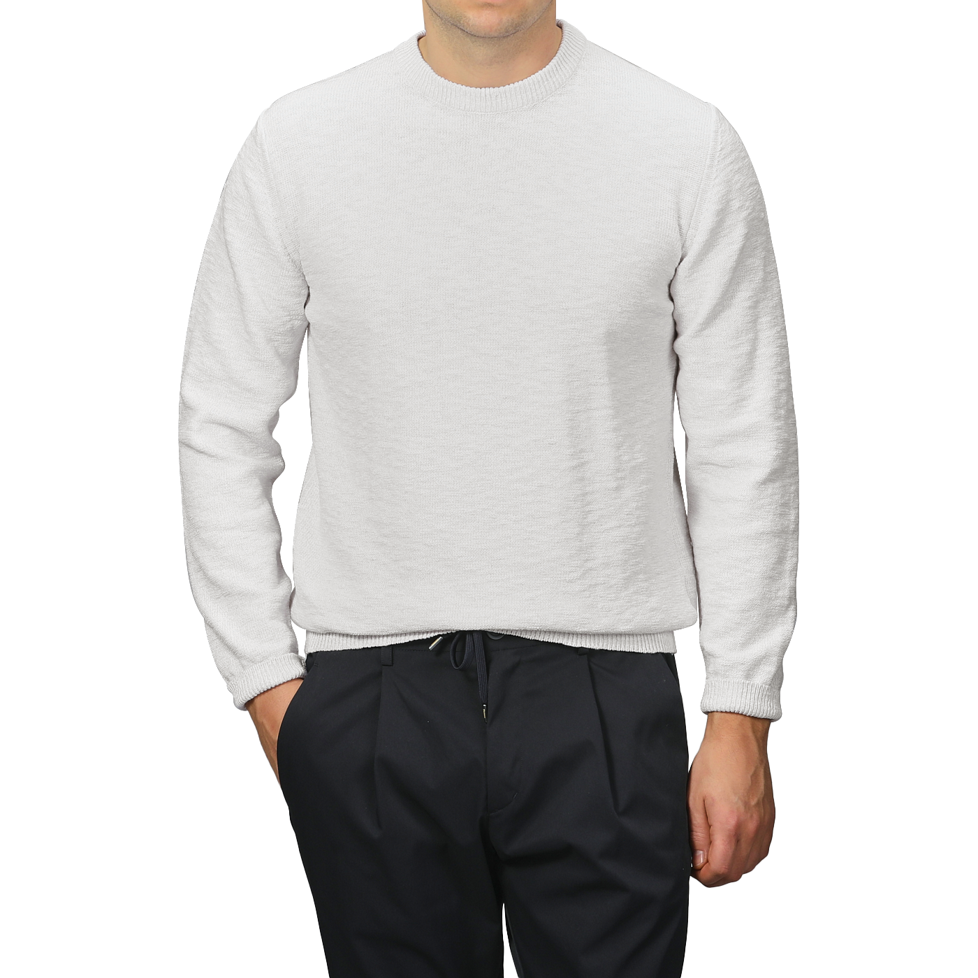 A person wearing a Maurizio Baldassari Cream Summer Mouline Crew Neck Sweater and black pants stands against a gray background, with hands partially in their pockets, highlighting the comfortable cotton-viscose blend.