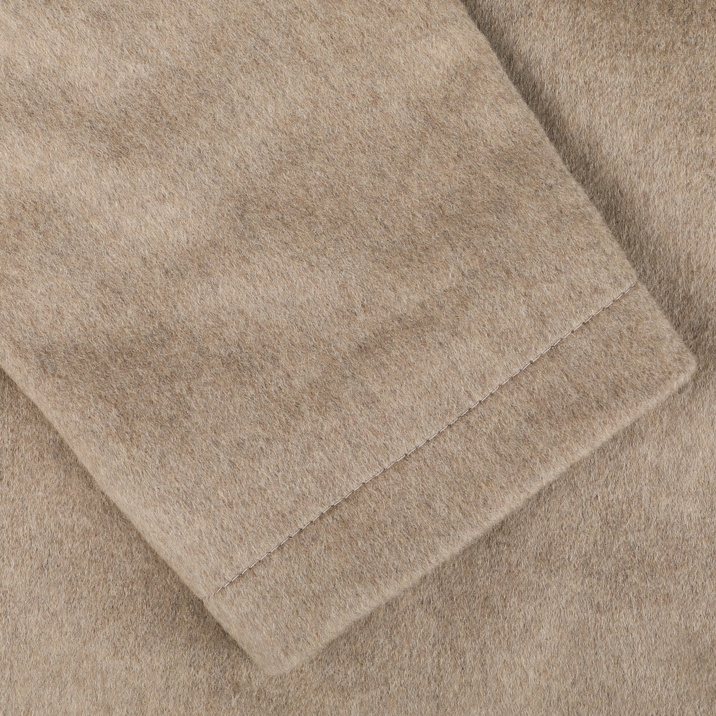 Close-up image of the Beige Cashmere Half Padded Chore Coat by Maurizio Baldassari, showcasing a seam detail that highlights its soft and slightly fuzzy texture reminiscent of luxury cashmere.