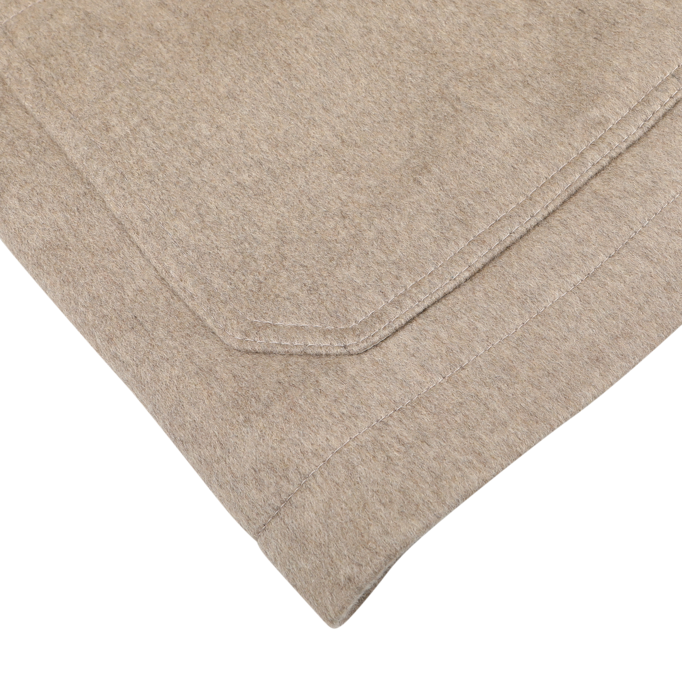 Close-up view of a beige folded fabric with visible stitching on a white surface, showcasing the texture and elegance of the Beige Cashmere Half Padded Chore Coat by Maurizio Baldassari.