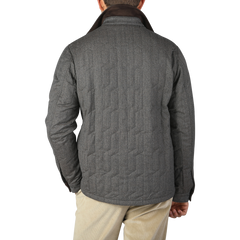 A person is standing with their back facing the camera, wearing a Taupe Beige Herringbone Quilted Virgin Wool Overshirt by Maurizio Baldassari and beige pants against a plain background.