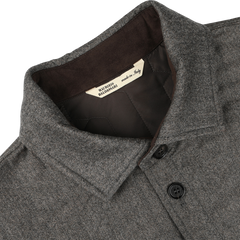 Close-up of a taupe beige herringbone quilted virgin wool overshirt collar with black buttons, showcasing a beige label inside that reads "Maurizio Baldassari made in Italy," and hinting at its subtle Thermore padding for added warmth.